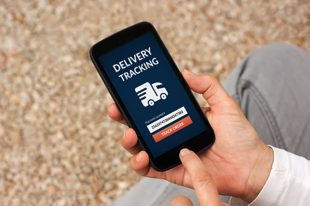Hands holding smart phone with delivery tracking concept on screen. All screen content is designed by meの写真素材