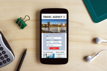 Travel agency concept on smart phone screen on wooden desk. All screen content is designed by me. Flat layの写真素材