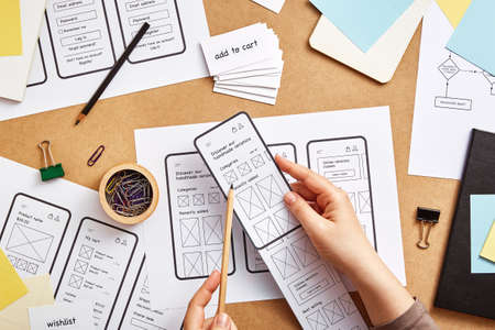UI / UX front end designer working on mobile responsive website. Flat lay image of several app wireframe sketches over product designer desk.の写真素材