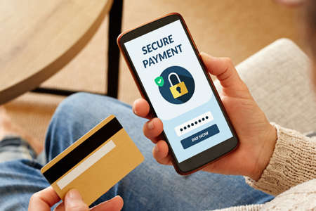 Secure online payment concept. Close-up of woman holding a credit card and paying online with smartphone.の写真素材
