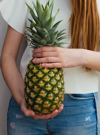 healthy girl with long red hair holding a pineappleの写真素材