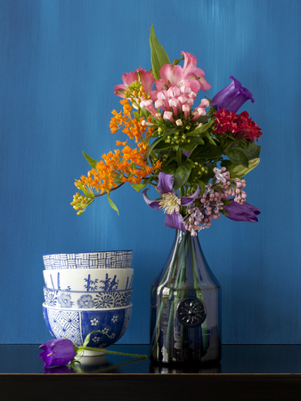 Beautiful still life with flowers in a vase and some bowls on a black tableの写真素材