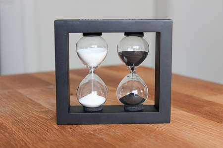 Hourglass standing on a wooden tableの写真素材