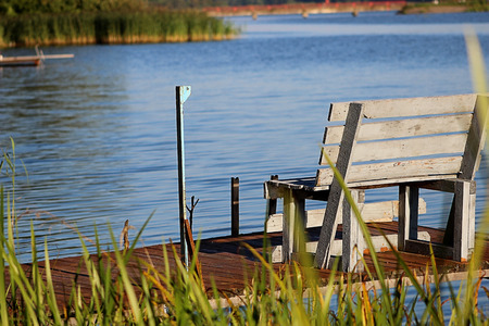 Wooden bench on the dock by the lake at sunsetの写真素材