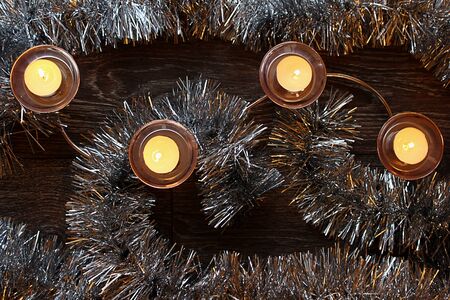 burning Christmas candles in candlesticks between the garlandの写真素材