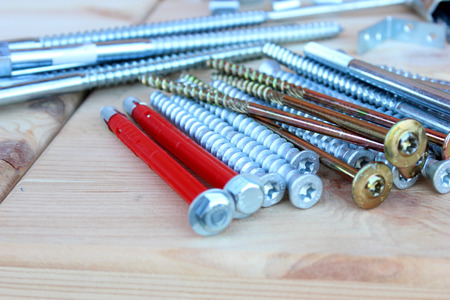 Anchors, screws and bolts of different lengths and shapes on the wooden boxesの写真素材