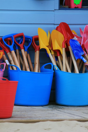 Gardening tools in blue and pink plastic buckets on the wooden floorの写真素材