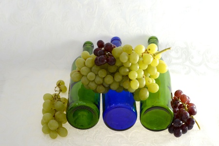 Four wine bottles laying down with red and green grapesの写真素材