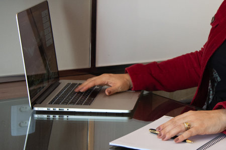 Businesswoman working on laptop computer at office desk with pen and notebookの写真素材