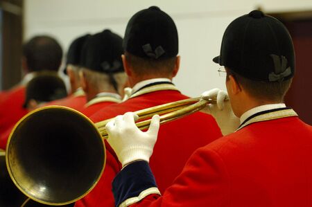 Back view of  musicians playing on hunting horn and with traditionnal red dress - fox hunting paradeの写真素材