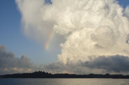Sunset landscape on a lake, with a rainbow and amazing clouds