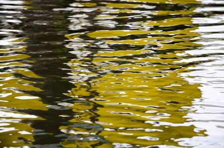 Color and nature: yellow reflection on moving water surfaceの写真素材