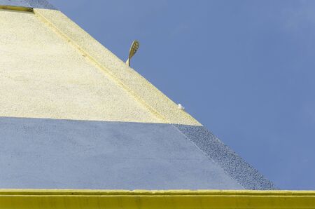 Urban detail, exterior of building painted light blue, cream and yellow, against a clear sky, in La...