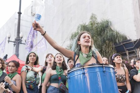 Capital Federal, Buenos Aires / Argentina; Feb 19, 2020: young woman shouting slogans and playing a drum in a demonstration in favor of the approval of the law of legal, safe and free abortionのeditorial素材