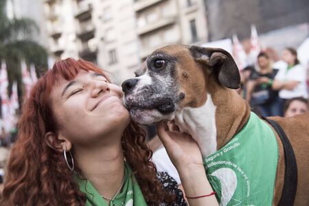 Capital Federal, Buenos Aires / Argentina; Feb 19, 2020: rally in favor of legal, safe and free abortion; a happy young woman and a boxer dog wearing green handkerchief, cause symbolのeditorial素材