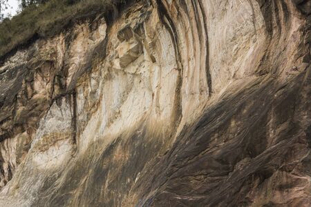Natural background, yellowish earth cliff wall with rough textureの写真素材