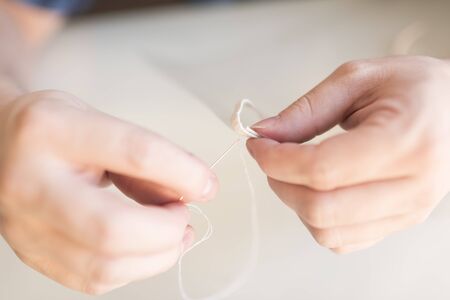 Hands sewing an elastic to an acetate plate. Process of making a homemade protective mask, to...