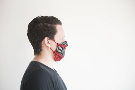 Side portrait of a young man wearing a homemade reusable fabric face mask, to prevent the spread of the coronavirus disease, Covid-19の写真素材