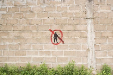 Carmelo, Colonia / Uruguay; Dec 27, 2018: concrete block wall with a painted symbol: a black soldier silhouette crossed out with red.のeditorial素材