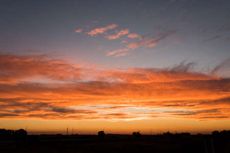 Sunset landscape, an orange bright intense sky and small silhouettes on the horizon, in Carmelo, Uruguay.のeditorial素材