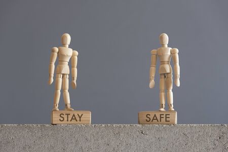 Image about the need for self-care, in relation to the coronavirus outbreak, covid-19. Pair of wooden human figures standing on blocks with the text Stay Safeの写真素材