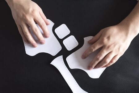 Hands arranging on synthetic leather paper templates. Materials to start making a homemade...