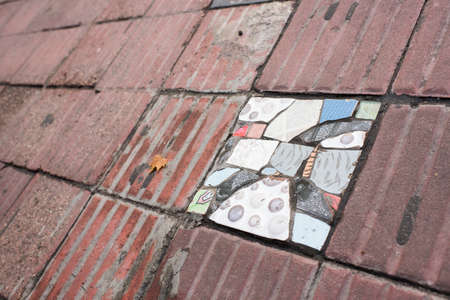 Sidewalk tile replaced by broken pieces of different colored tilesのeditorial素材