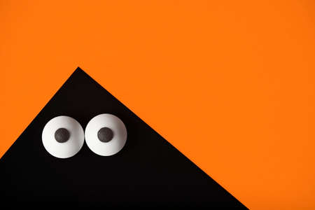 Halloween background, Black ghost with bulging eyes on orange, copy space.の写真素材