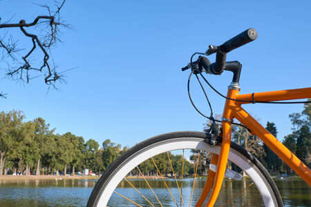 Orange bicycle on the edge of a lake in the large public park known as Bosques de Palermo, in Buenos Aires, Argentinaの写真素材
