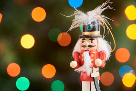 Traditional wooden Christmas nutcracker with a green background with colored lights out of focus,...