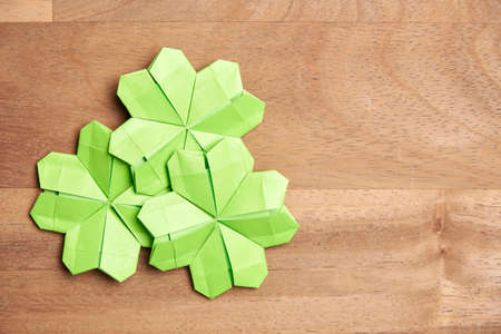 Origami four-leaf clovers, made of light green paper, on a wooden background. Concepts of luck and St. Patrick's Day. Image with copy space.の写真素材