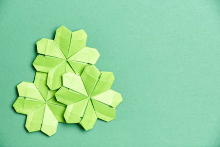 Origami four-leaf clovers, made of light green paper, on green background. Concepts of luck and St. Patrick's Day. Image with copy space.の写真素材