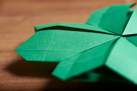 Macro image of a four-leaf clover made of green paper folded following the origami technique, on a...
