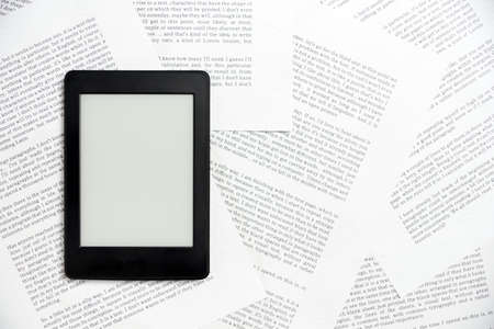 Electronic reader off on sheets of paper with text printed on them. Concepts: reading and digital...