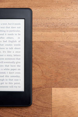 Closeup image of an electronic reader with blank screen on a wooden surface. Concepts of technology...