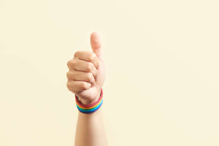 Young hand with a rainbow bracelet, LGBT symbol, showing thumbs up. Concepts of love, sexual...