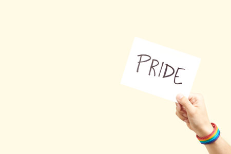 Young hand with a rainbow bracelet, LGBT symbol, holding a piece of paper with a handwritten message: pride. Concepts of love, sexual diversity and non-discrimination. Image with copy space.の写真素材