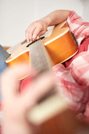 Unrecognizable young man playing guitar at home. Concepts of music, hobbies and leisure time....