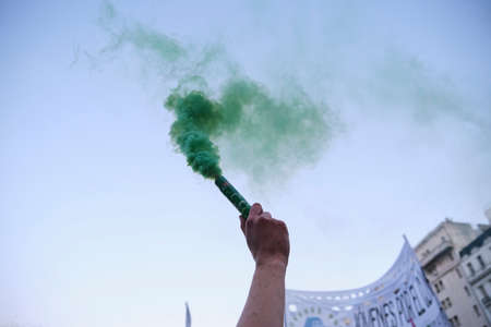 Buenos Aires, Argentina; Sept 24, 2021: Global Climate Strike, arm raising a green smoke flare as...