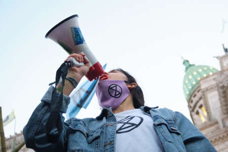 Buenos Aires, Argentina; Sept 24, 2021: Global Climate Strike, young female activist from XR, Rebellion Extinction, use a megaphone to speak about the climate crisis in front of the National Congressのeditorial素材