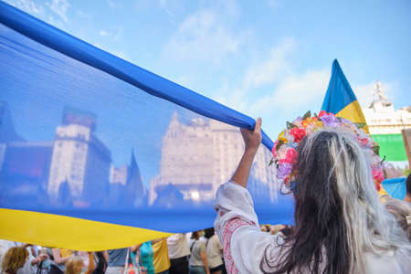 Buenos Aires, Argentina; March 6, 2022: march for peace in Ukraine, against Russian war and invasion. People raising a large Ukrainian flag.のeditorial素材
