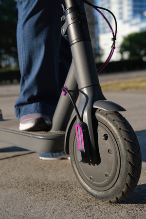 Close-up image, woman legs with her electric kick scooter in the city a sunny morning. Concepts of sustainability, modernity, clean energy and green mobility, eco transportation.の写真素材