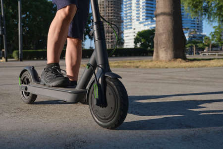 Unrecognizable man with his electric kick scooter in the city on a sunny morning. Concepts of...