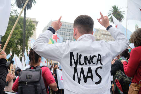 Buenos Aires, Argentina; March 24, 2022: National Day of Remembrance for Truth and Justice, gathering of people in Plaza de Mayo; a man on his back, arms raised, on his back is written Never againのeditorial素材