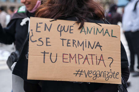 Buenos Aires, Argentina; Nov 1, 2021: World Vegan Day, unrecognizable person carries a sign on his back with the text On which animal does your empathy end? Veganize yourself.のeditorial素材