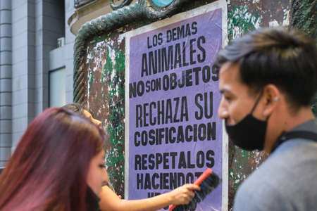 Buenos Aires, Argentina; Nov 1, 2021: World Vegan Day, People sticking a sign in favor of veganism:...