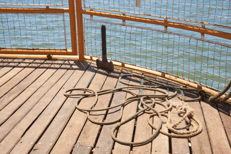 Detail of the bow of a tourist boat sailing in the summer sun, mooring rope on deck timbers....