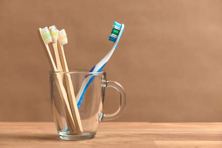 Toothbrushes, a plastic one and a set of three ecological made of bamboo. Concepts: sustainable...