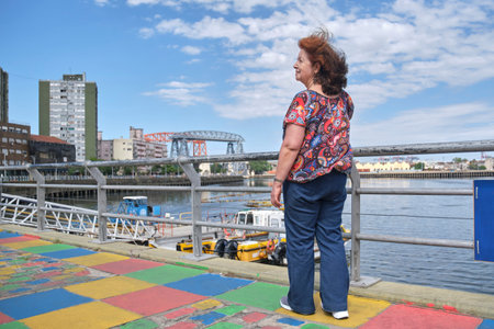 Mature latin woman taking a selfie with her smartphone in the touristic neighborhood of La Boca, in Buenos Aires, Argentina, on a sunny summer day.の写真素材