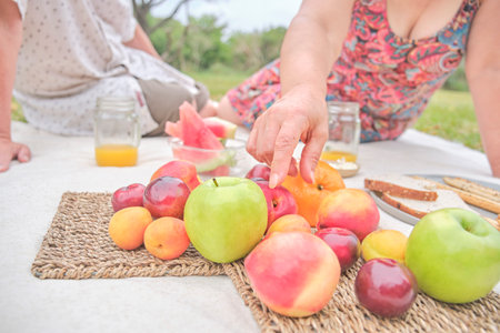 Unrecognizable couple having a picnic breakfast with a variety of fruits. Concepts: healthy eating, enjoying the outdoors at summer time.の写真素材